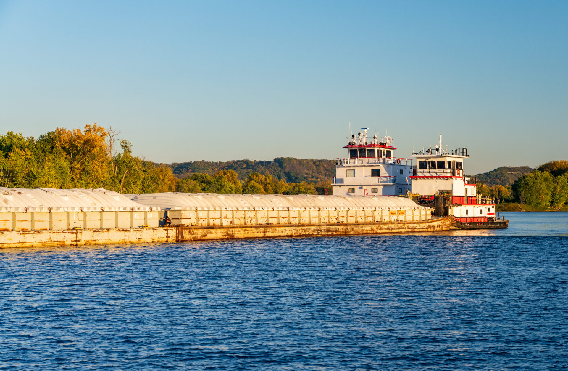 Large river barge on Upper Mississippi being pushed by pair of tugs AdobeStock_684223211 MS River Barge